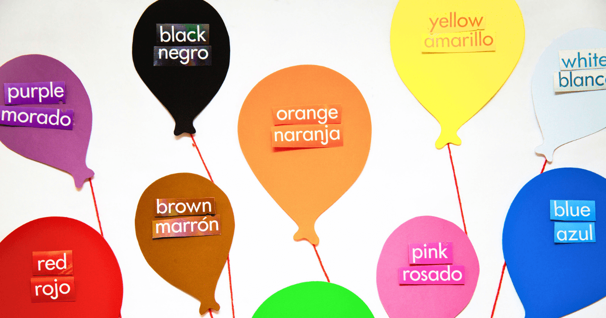 Vibrant cut-out balloons feature their color names in English and Spanish, making them perfect for a bilingual preschool learning environment. Colors include red/rojo, purple/morado, black/negro, brown/marrón, and more.