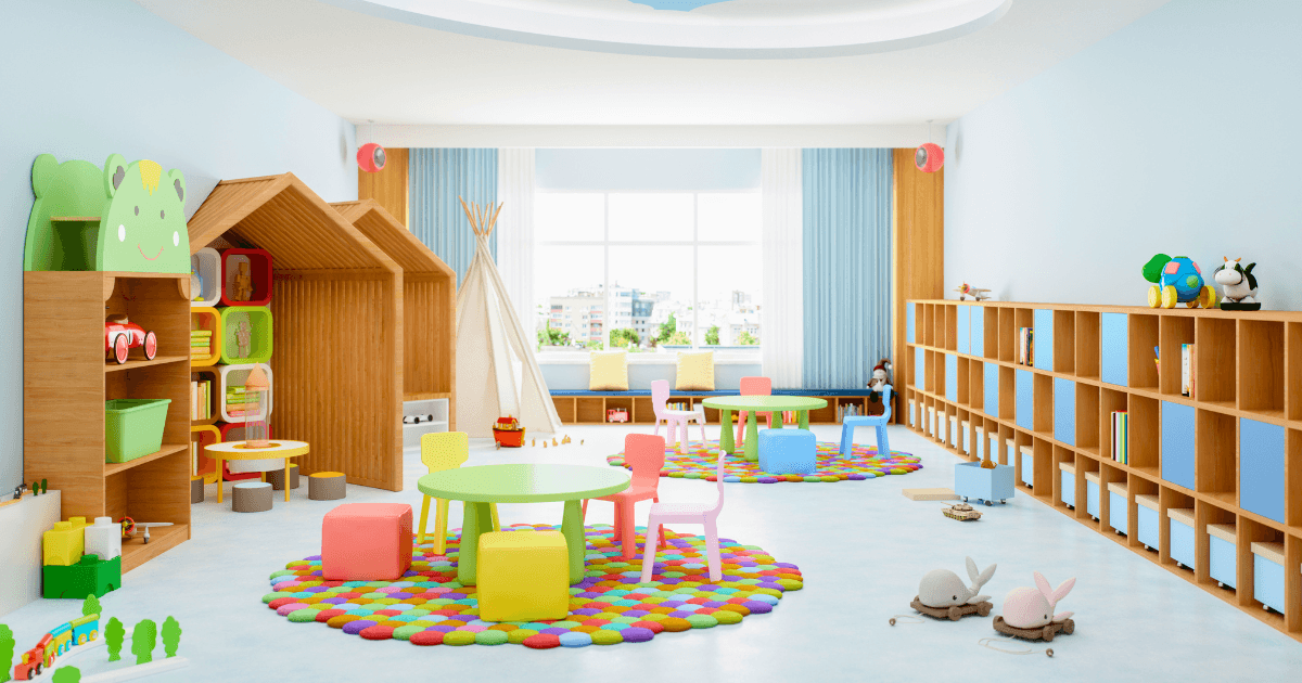 A brightly lit, colorful classroom with budget-friendly classroom materials, round tables, small chairs, bookshelves, toys, and play mats. Playful decorations, a playhouse, a teepee tent, and large windows let in natural light.