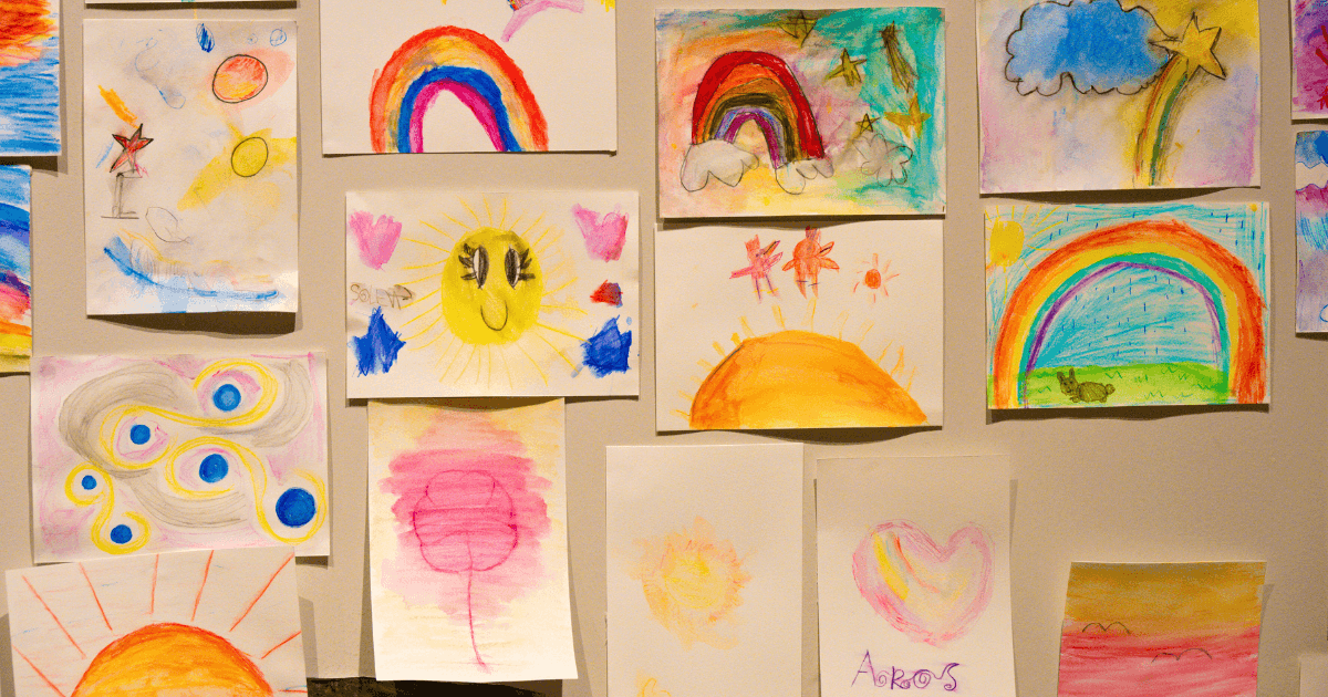 A wall covered with colorful children's drawings, featuring rainbows, suns, clouds, stars, and hearts—displayed as vibrant documentation panels crafted with crayons and watercolors on white paper.