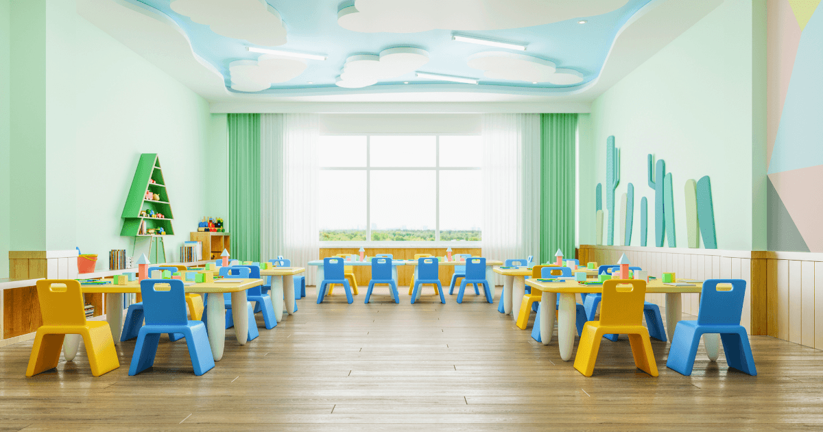 A bright, colorful classroom with small blue and yellow chairs around white tables showcases thoughtful classroom organization. Toys and books are on shelves against pastel green walls, while large windows and playful cloud designs create a cheerful atmosphere.